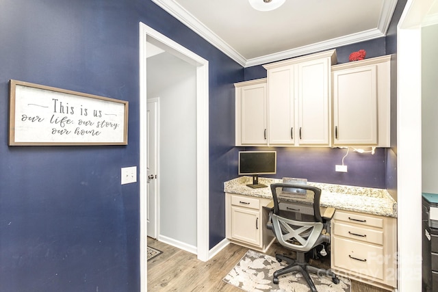 office area with light wood-type flooring, built in desk, and crown molding