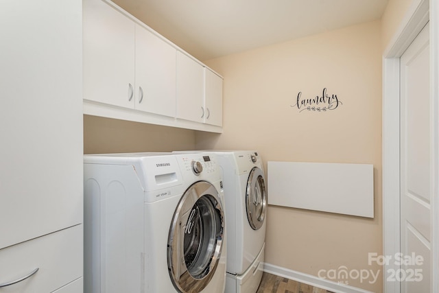 washroom featuring washing machine and clothes dryer, hardwood / wood-style floors, and cabinets