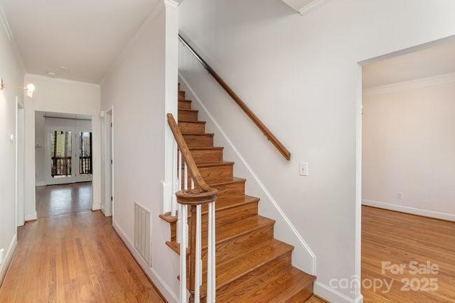 staircase with hardwood / wood-style flooring and crown molding