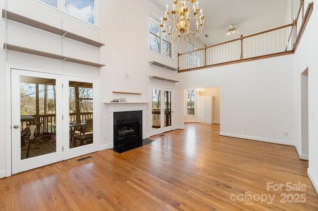 unfurnished living room with french doors, a towering ceiling, and hardwood / wood-style flooring