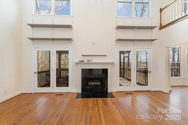 unfurnished living room with a fireplace, a wealth of natural light, and french doors