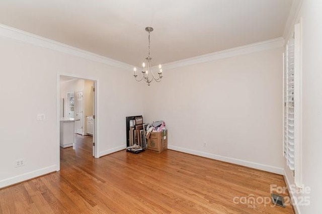 unfurnished room featuring hardwood / wood-style flooring, a notable chandelier, and ornamental molding