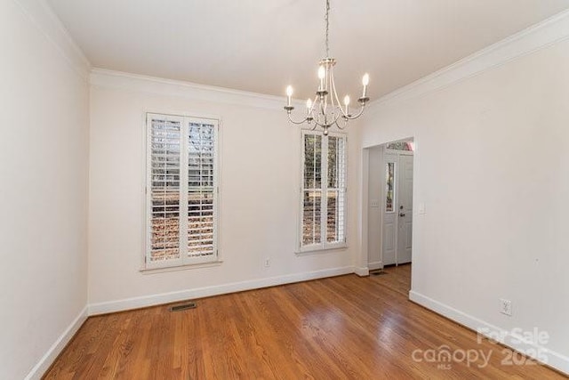 unfurnished dining area featuring hardwood / wood-style flooring, ornamental molding, and an inviting chandelier