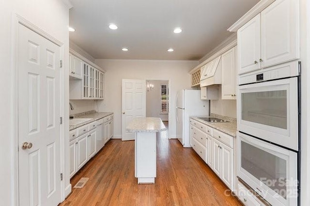 kitchen with light wood-type flooring, white appliances, sink, a center island, and white cabinetry