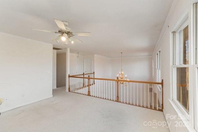 unfurnished room featuring carpet, ceiling fan with notable chandelier, and crown molding