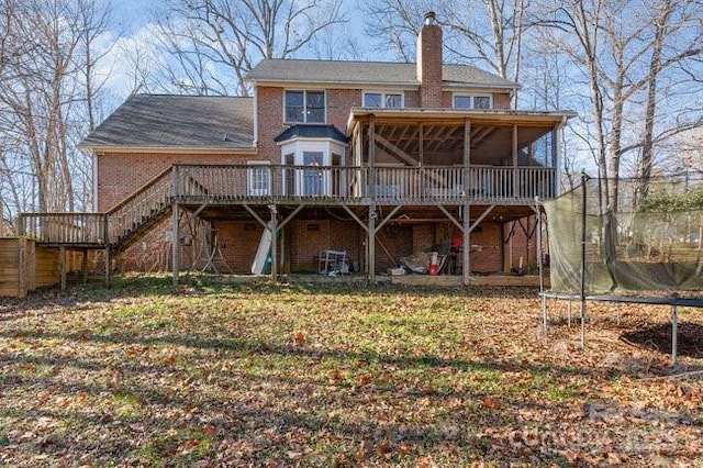 back of property featuring a deck and a trampoline