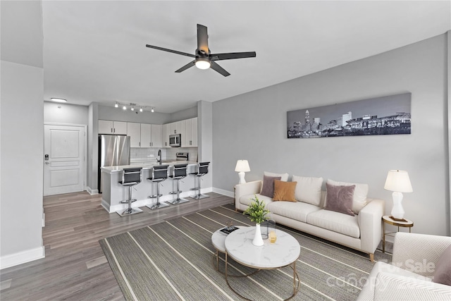 living room with dark wood-type flooring, ceiling fan, and sink