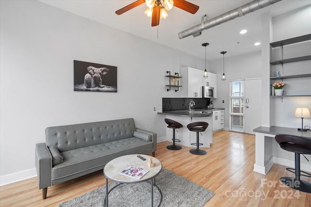 living room featuring light wood-type flooring, ceiling fan, and sink