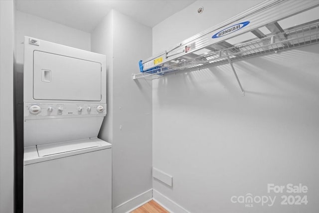 laundry area with light wood-type flooring and stacked washing maching and dryer