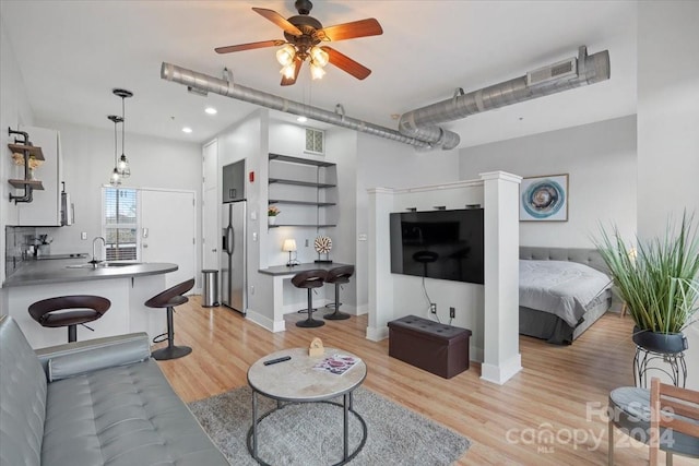 living room with ceiling fan, light hardwood / wood-style flooring, and sink