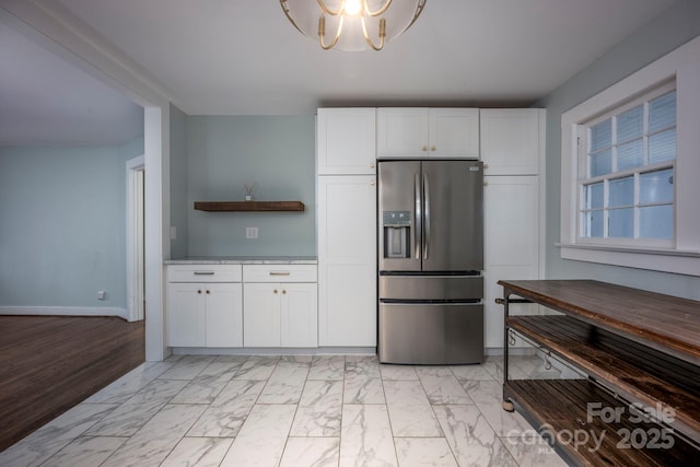 kitchen featuring white cabinets, stainless steel fridge, and an inviting chandelier