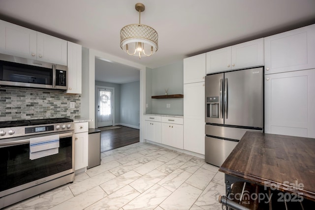 kitchen with decorative backsplash, pendant lighting, white cabinets, and stainless steel appliances