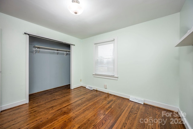 unfurnished bedroom featuring a closet and dark wood-type flooring