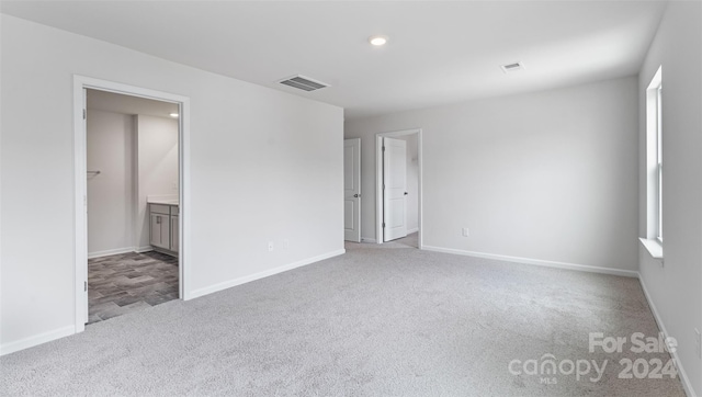 unfurnished bedroom featuring connected bathroom and light colored carpet