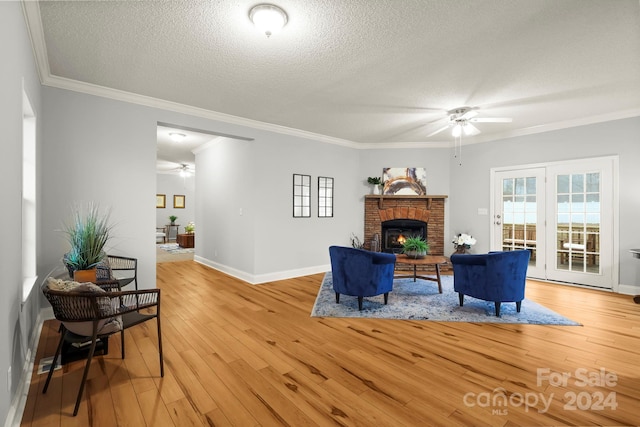 living room featuring hardwood / wood-style flooring, a fireplace, a textured ceiling, and ornamental molding