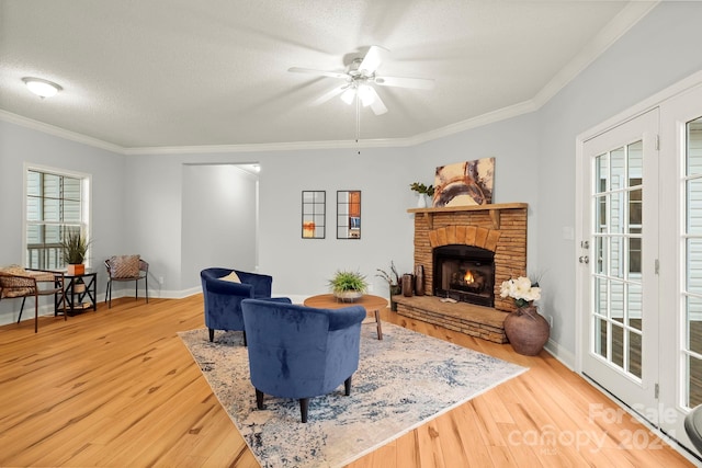 living room with a textured ceiling, a stone fireplace, wood-type flooring, and crown molding