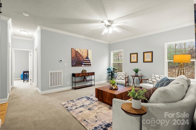 living room with a textured ceiling, ceiling fan, ornamental molding, and light carpet