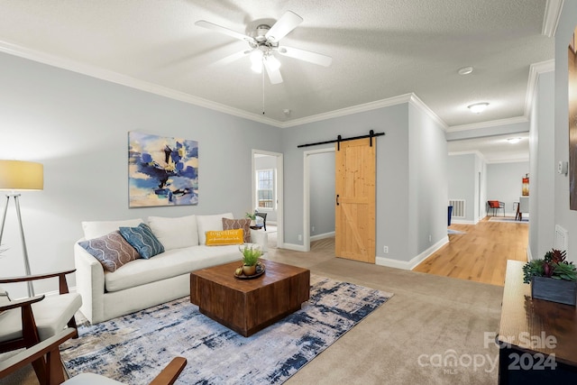 living room featuring carpet, a textured ceiling, ceiling fan, crown molding, and a barn door