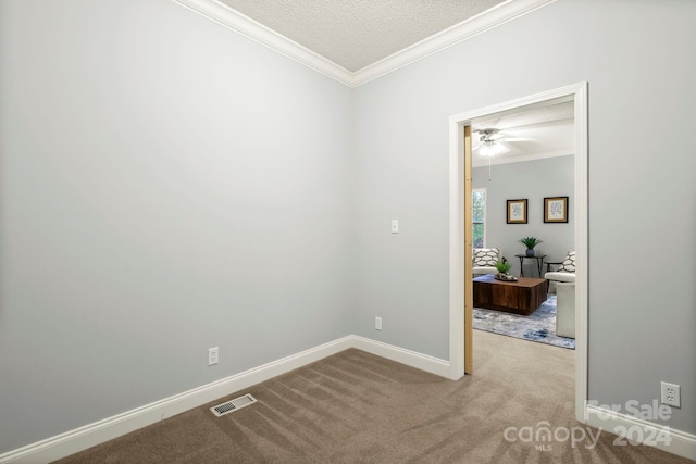 unfurnished room with crown molding, light colored carpet, and a textured ceiling