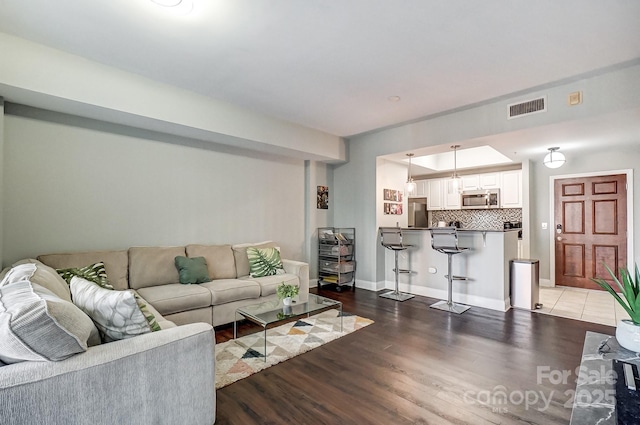 living room with light wood-style floors, baseboards, and visible vents