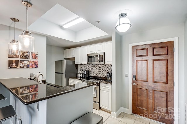 kitchen with tasteful backsplash, a breakfast bar area, appliances with stainless steel finishes, white cabinetry, and a sink