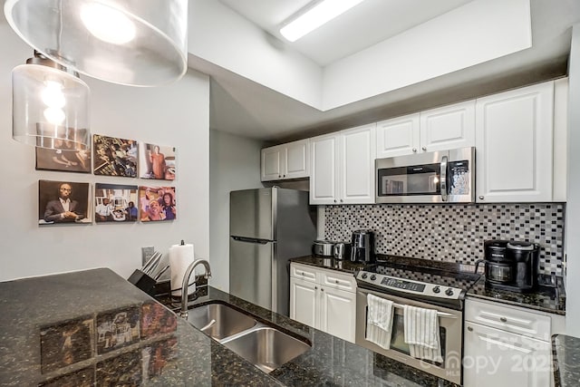 kitchen with appliances with stainless steel finishes, a sink, white cabinets, and tasteful backsplash