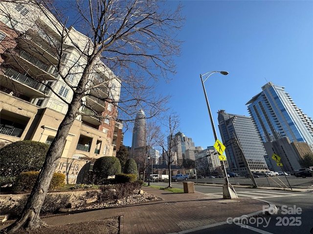 view of road with street lighting, curbs, traffic signs, a city view, and sidewalks