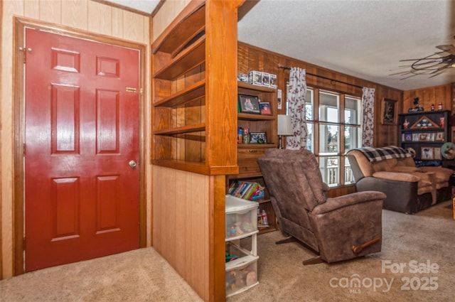 foyer with ceiling fan, wood walls, carpet floors, and a textured ceiling