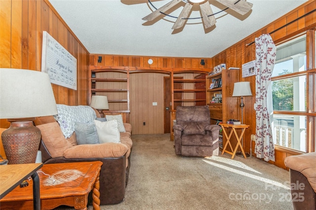 carpeted living room featuring ceiling fan and wood walls