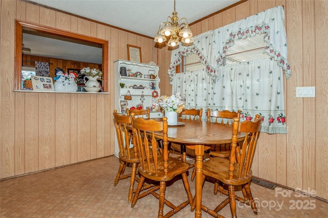 dining room featuring crown molding, a notable chandelier, and wood walls