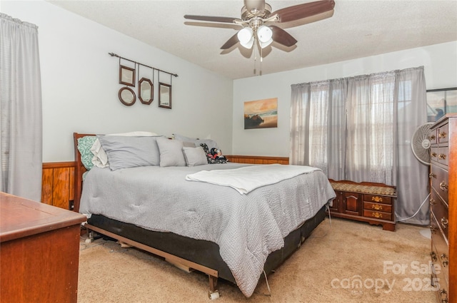 carpeted bedroom with a textured ceiling, ceiling fan, and wooden walls