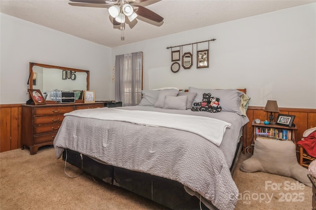 carpeted bedroom featuring ceiling fan and wood walls