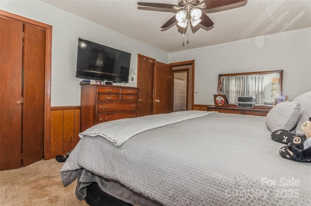 carpeted bedroom with a closet, ceiling fan, wooden walls, and a textured ceiling