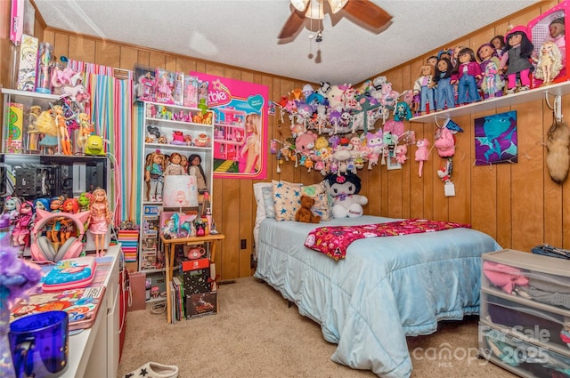 carpeted bedroom with ceiling fan, a textured ceiling, and wooden walls