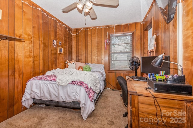 carpeted bedroom featuring wood walls, ceiling fan, and a textured ceiling