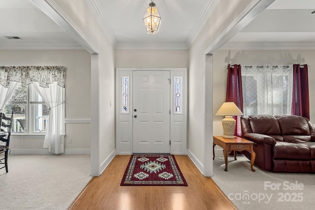 foyer with carpet flooring, an inviting chandelier, and ornamental molding