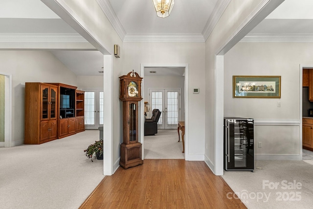 carpeted entrance foyer featuring crown molding, wine cooler, and french doors