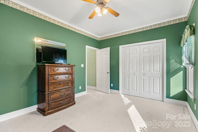 carpeted bedroom with a closet, ornamental molding, and ceiling fan