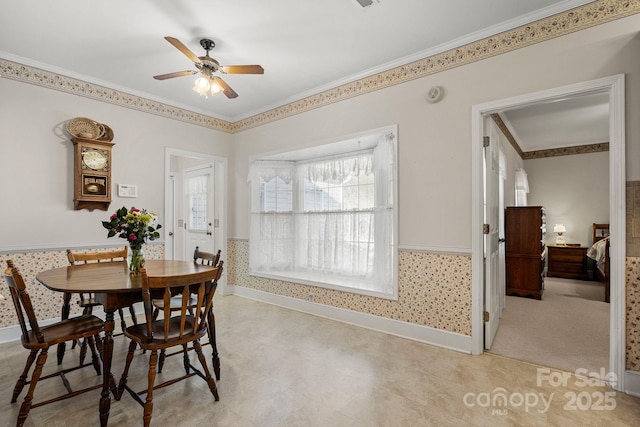 carpeted dining room featuring ceiling fan and crown molding