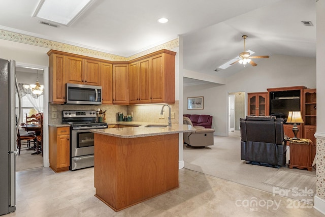 kitchen featuring kitchen peninsula, decorative backsplash, ceiling fan with notable chandelier, stainless steel appliances, and sink