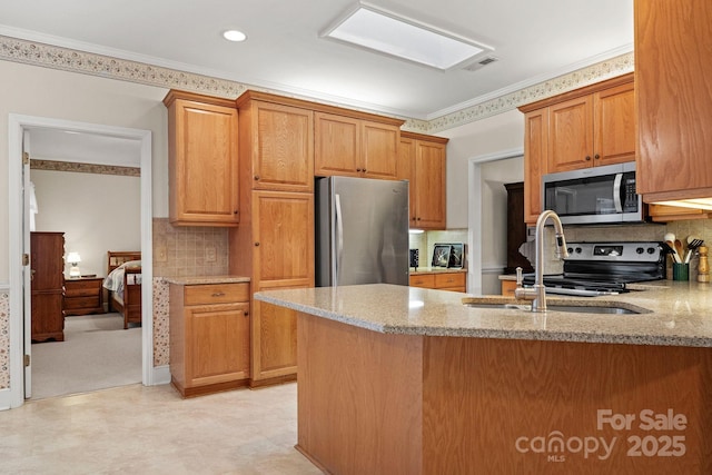 kitchen featuring sink, a skylight, tasteful backsplash, light stone counters, and stainless steel appliances