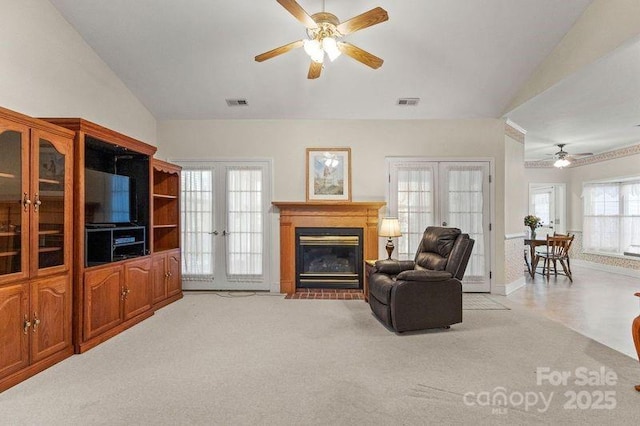 carpeted living room with ceiling fan, lofted ceiling, and french doors