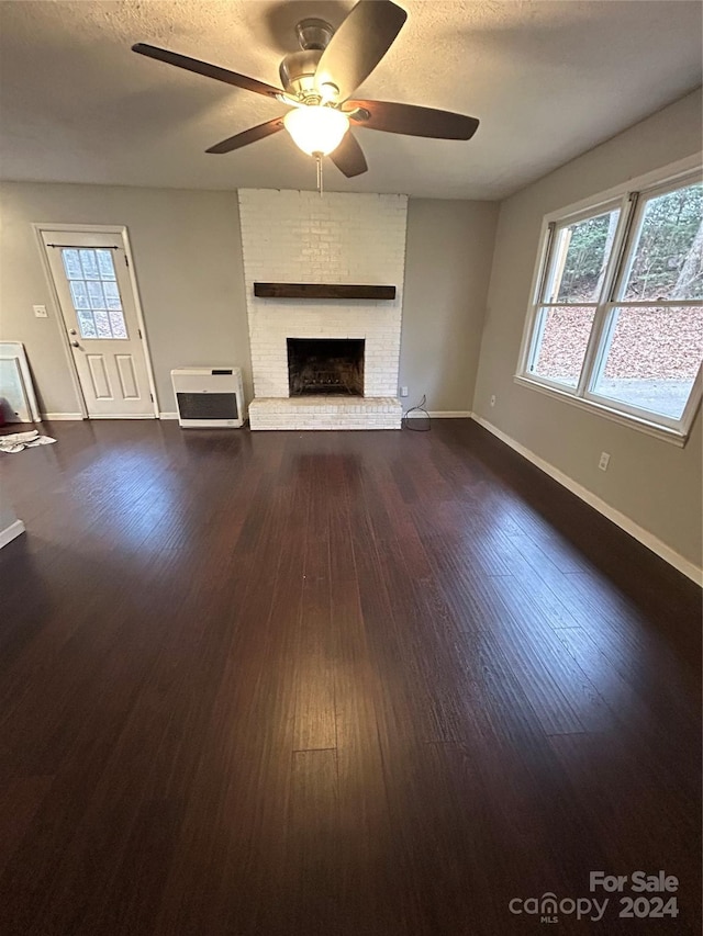 unfurnished living room featuring ceiling fan, dark hardwood / wood-style floors, a textured ceiling, and a brick fireplace