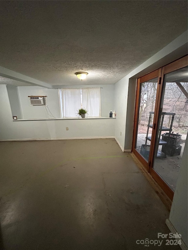 unfurnished room with a wall mounted AC, concrete floors, and a textured ceiling