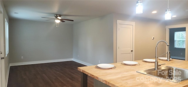 kitchen featuring ceiling fan, sink, hanging light fixtures, and dark hardwood / wood-style floors