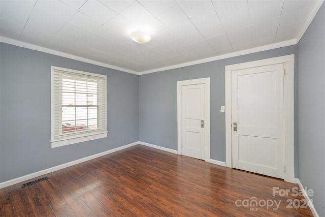 empty room featuring dark hardwood / wood-style flooring and crown molding