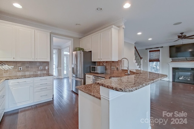 kitchen featuring backsplash, kitchen peninsula, white cabinets, and stainless steel appliances