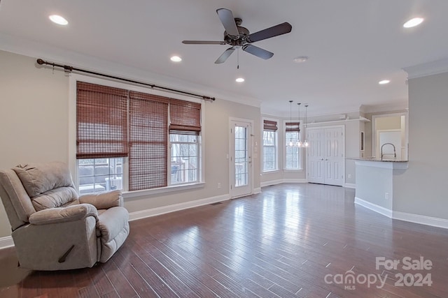 unfurnished living room featuring sink, ceiling fan with notable chandelier, dark hardwood / wood-style flooring, and crown molding