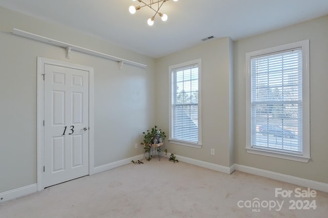 carpeted empty room with a notable chandelier