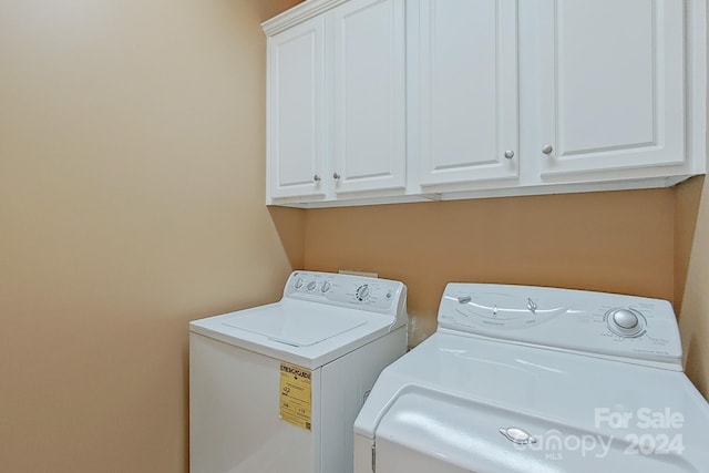 washroom with cabinets and washing machine and dryer